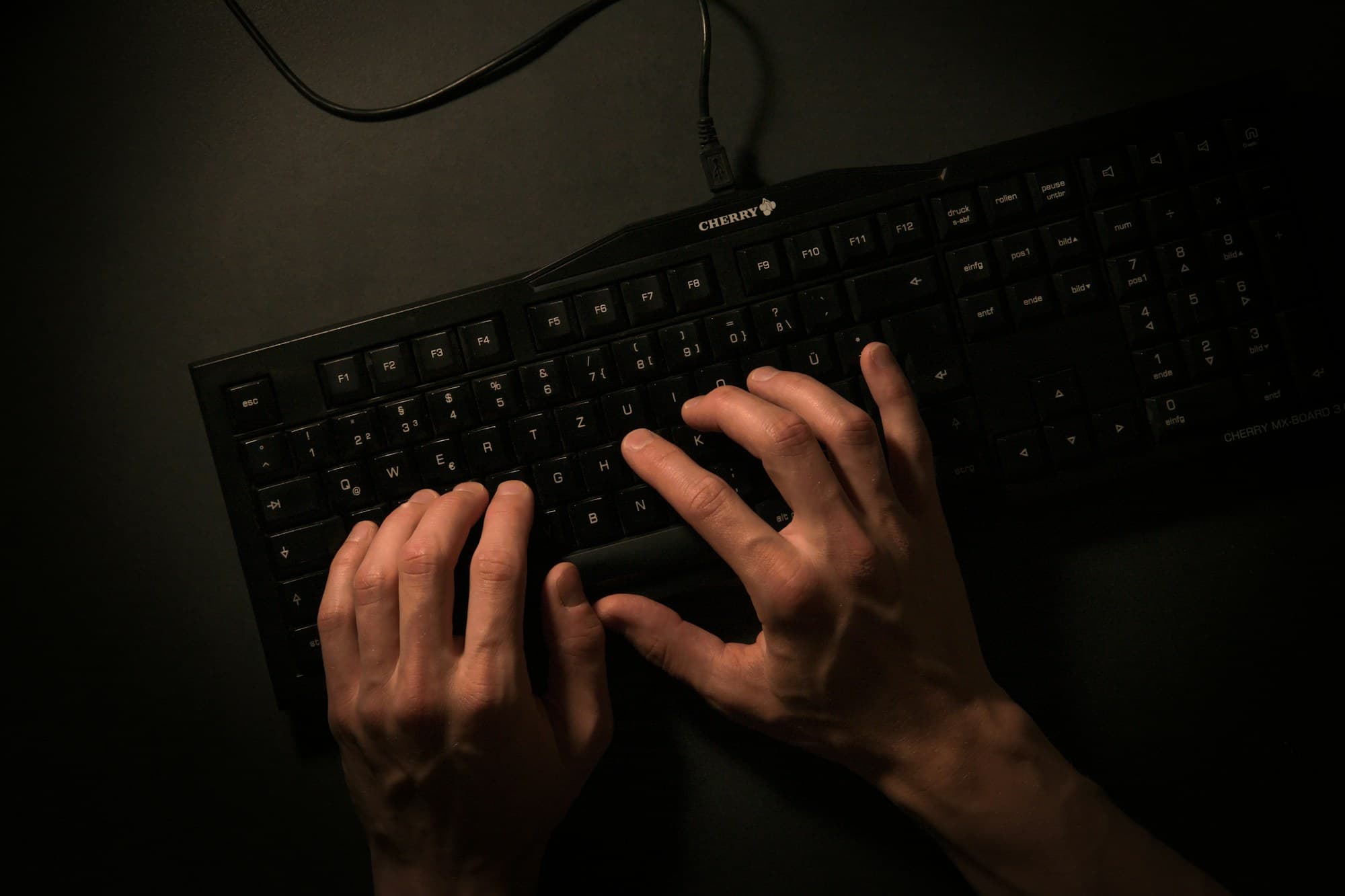 Mains posées sur un clavier, en lumière rasante